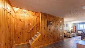 A wooden interior with a staircase, a sofa, and a window. - Shamrock condo courtyard area features a bike wash rack, pickleball/tennis court, basketball court, covered pavilion, grills, firepit and playground!  Inside the condo there is space for everyone!  Ample parking and easy access to walking path. (Snowshoe)