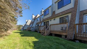 A row of mobile homes with wooden decks and steps leading to the entrance. - Shamrock condo courtyard area features a bike wash rack, pickleball/tennis court, basketball court, covered pavilion, grills, firepit and playground!  Inside the condo there is space for everyone!  Ample parking and easy access to walking path. (Snowshoe)