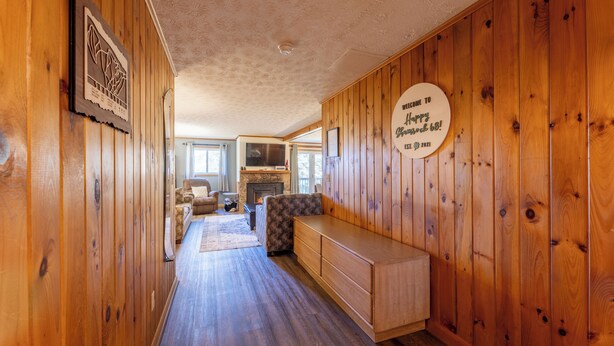 A wooden interior with a fireplace, a bench, and a welcome sign. - Shamrock condo courtyard area features a bike wash rack, pickleball/tennis court, basketball court, covered pavilion, grills, firepit and playground!  Inside the condo there is space for everyone!  Ample parking and easy access to walking path. (Snowshoe)