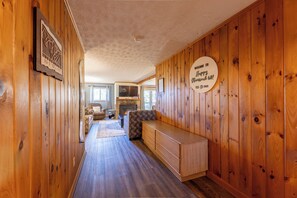Een houten interieur met een open haard, een bank en een welkomstbord.
