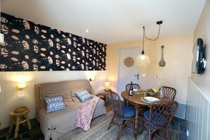 A cozy living area with a sofa, a dining table with chairs, and a wall with a leaf pattern.