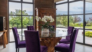 A dining area with a glass table surrounded by purple chairs, a wooden cabinet, and a potted orchid. - Villa Francesca Relais (Gradara)