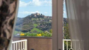 A balcony with a view of a castle on a hill, surrounded by greenery. - Villa Francesca Relais (Gradara)