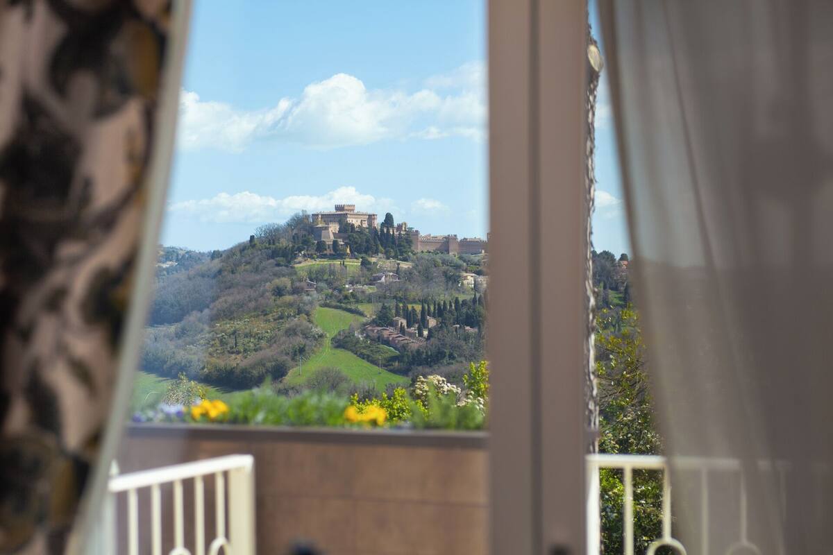 Un balcón con vistas a un castillo en una colina, rodeado de vegetación.