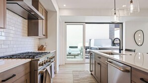 A modern kitchen with a gas stove, stainless steel appliances, and a large island. - Desert Dream Villa at Desert Color By Ember Stays (St. George)