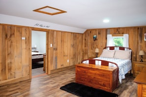 Un dormitorio con paneles de madera, una cama, mesitas de noche y una alfombra negra.
