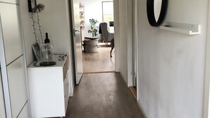Una cocina moderna con armarios blancos, encimera de madera y una lámpara colgante.