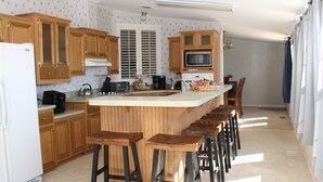 Una cocina con armarios de madera, un refrigerador blanco, un microondas y una isla grande con taburetes de bar.