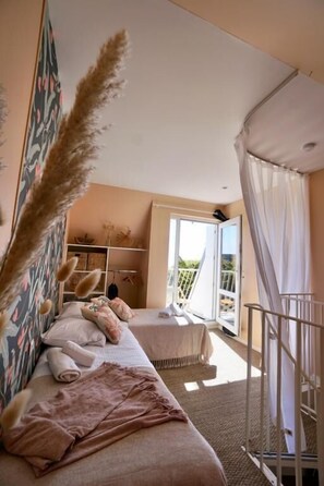 Quarto com duas camas, um guarda-roupa e uma varanda.