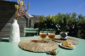 Uma mesa posta com duas cervejas, uma garrafa de vinho, um prato de biscoitos e um vaso com flores secas.