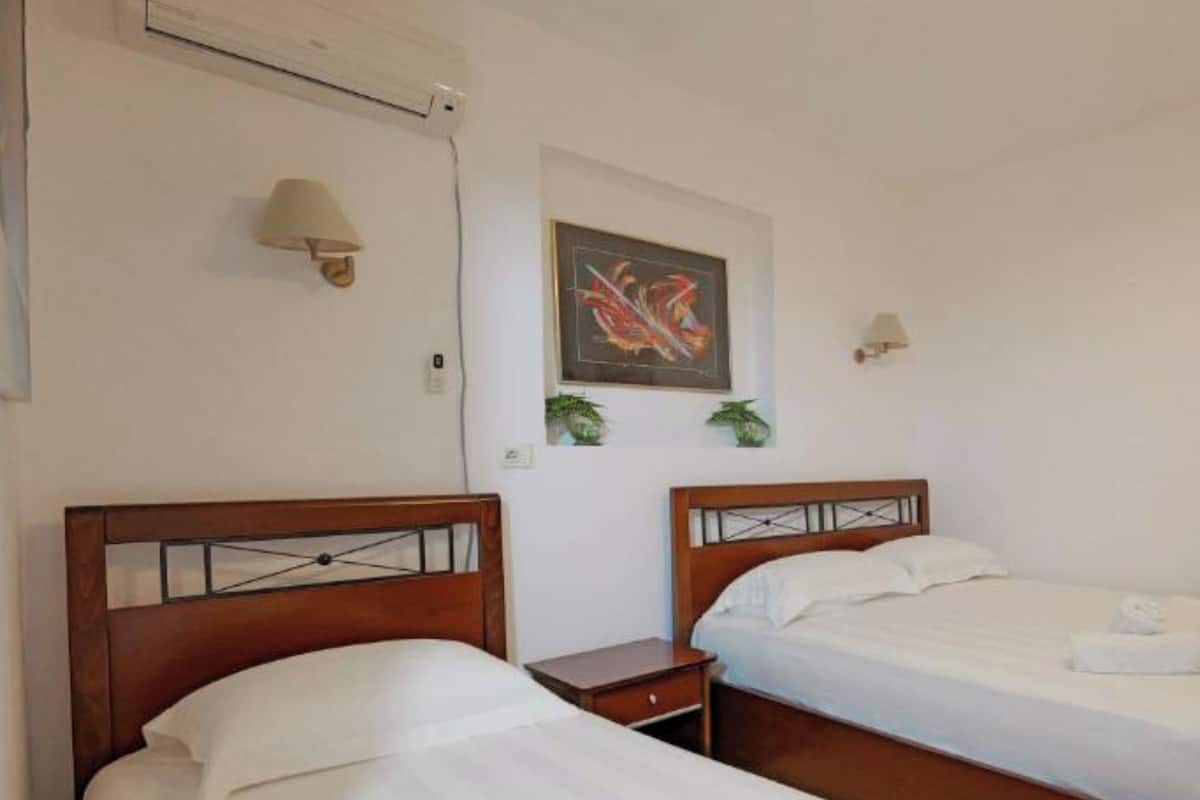 Dos camas individuales con cabeceros de madera, ropa de cama y toallas blancas.