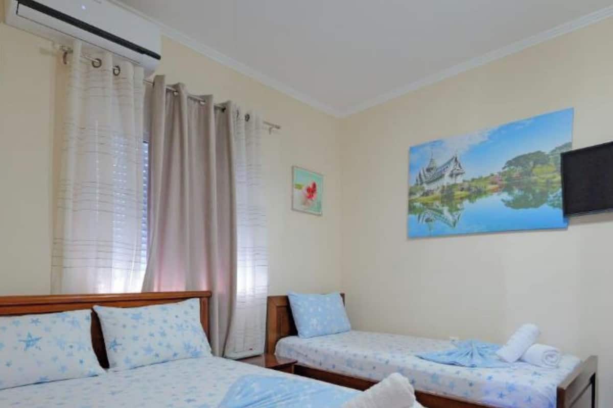 Una habitación de hotel con dos camas, un cuadro de un paisaje y una ventana con cortinas.