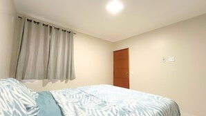 Un dormitorio con cama, cortinas, una puerta y una lámpara.