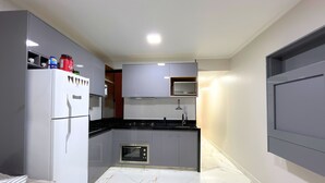 Una cocina compacta con refrigerador, horno, microondas y una pequeña isla con pileta.