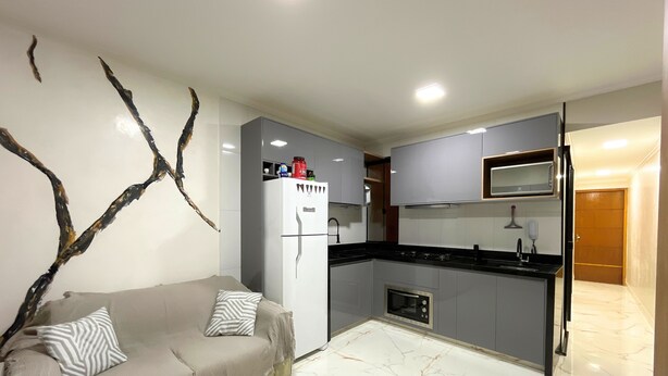 Una cocina compacta con sofá, refrigerador y microondas.