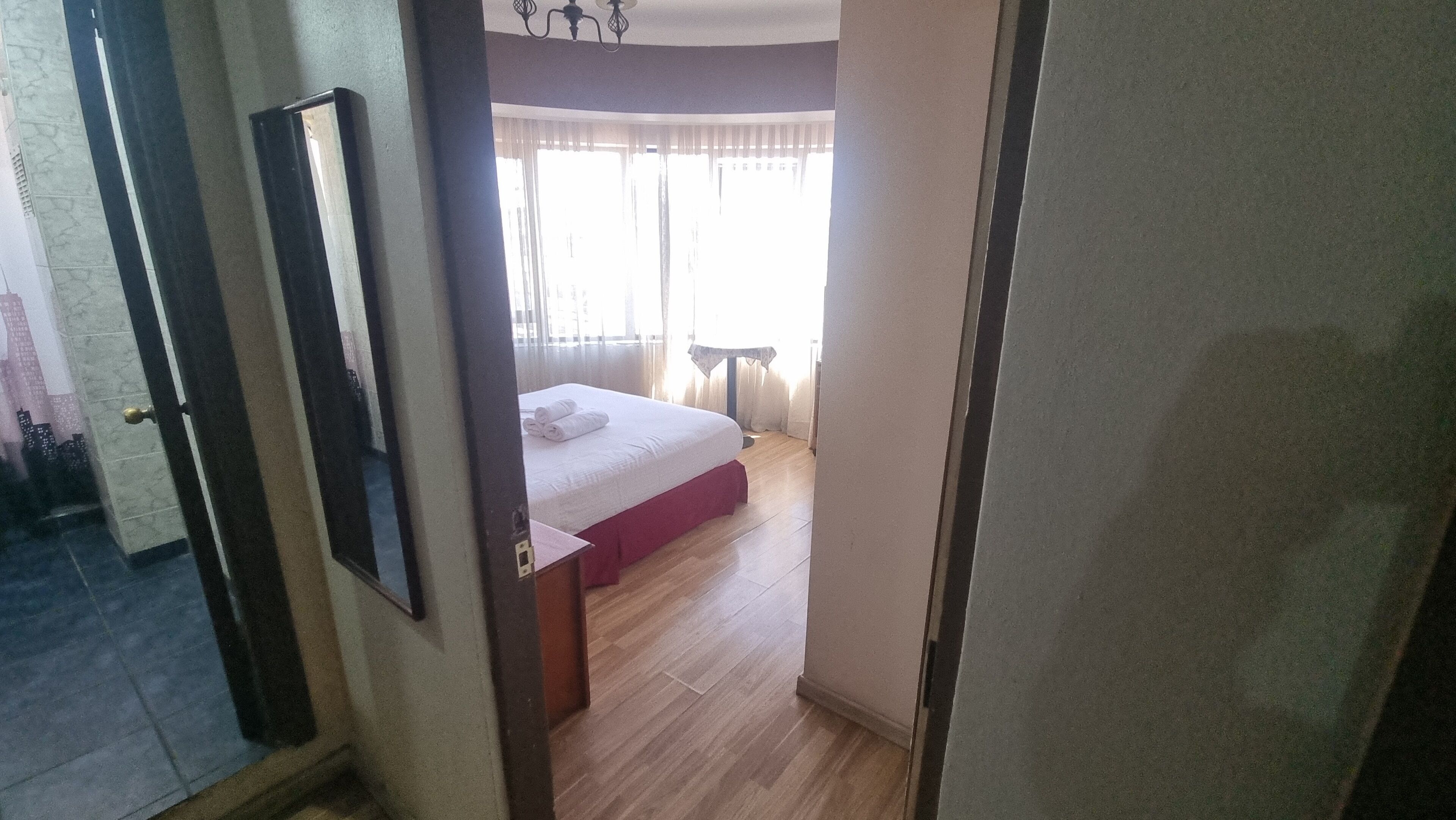 Una habitación de hotel con una cama, una mesita y una ventana con cortinas.
