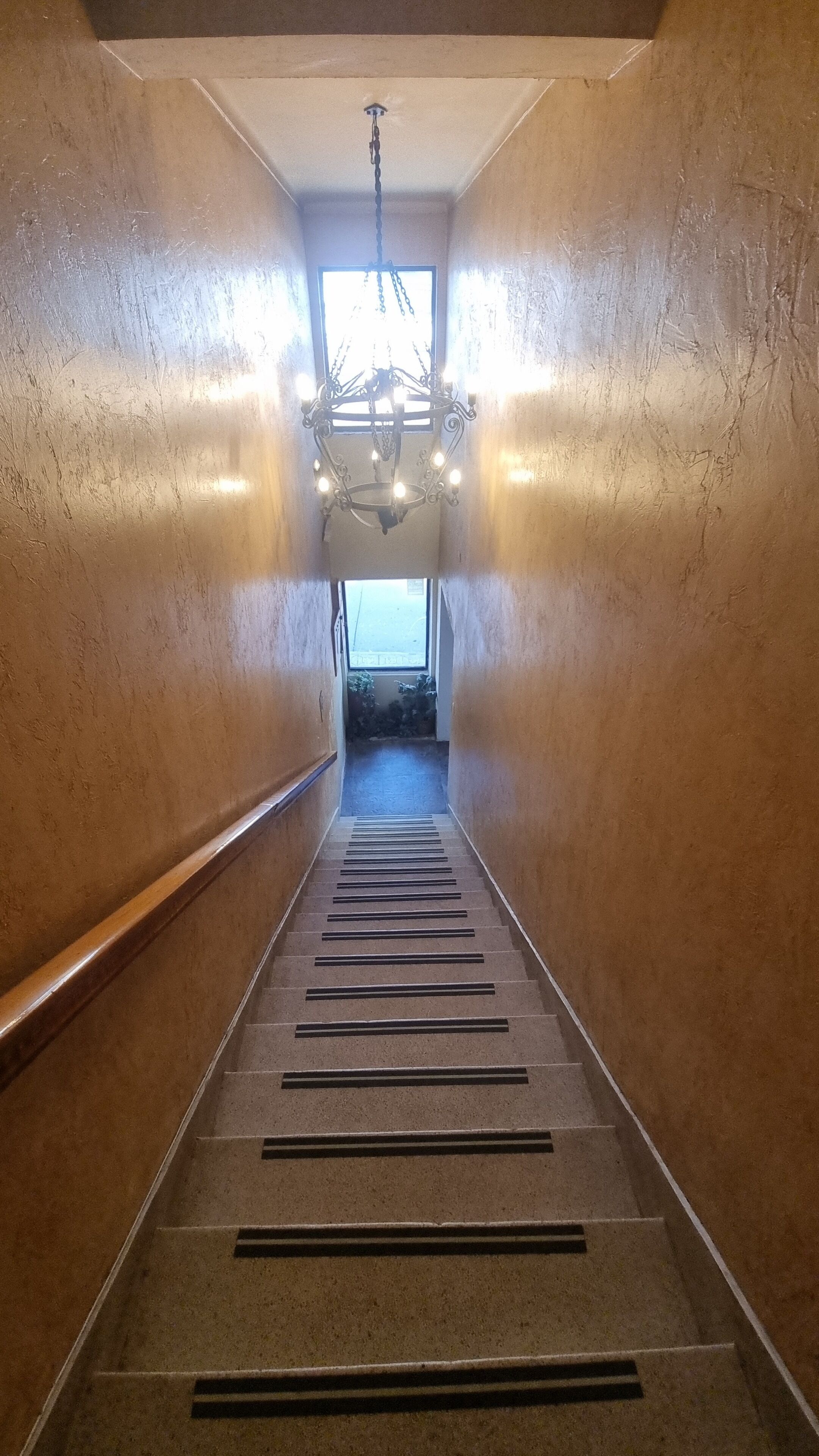 Ein Flur mit einem Kronleuchter, einem Fenster am Ende und einer Tür.