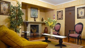 A room with a yellow armchair, a fireplace, framed artwork, and two upholstered chairs. - Hotel Dikran (Los Angeles)