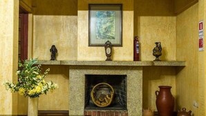 A fireplace with a framed picture above it, a clock, and decorative items on the mantel. - Hotel Dikran (Los Angeles)
