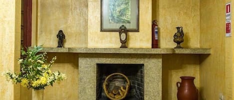 A fireplace with a framed picture above it, a clock, and decorative items on the mantel.