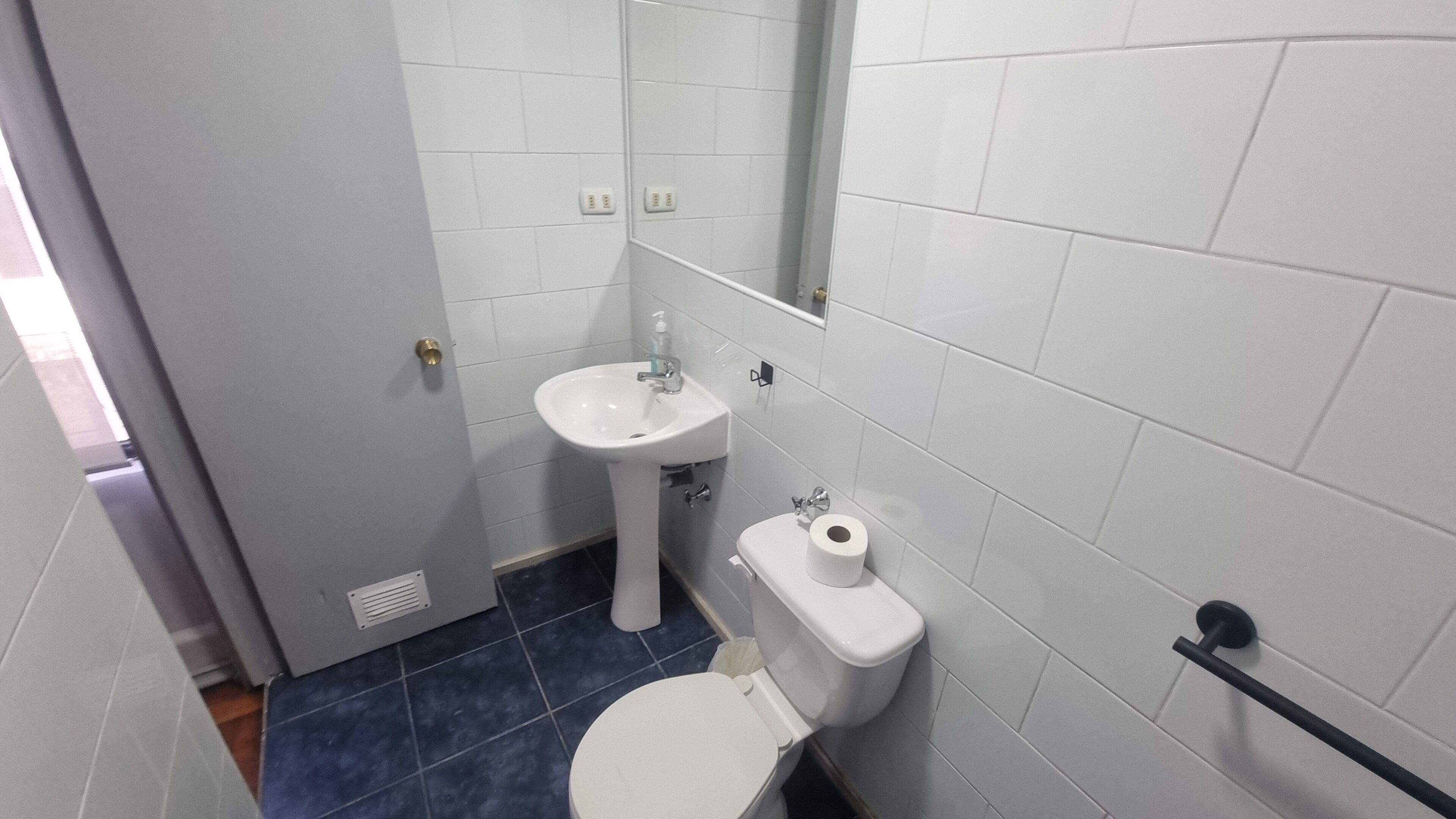 Un baño pequeño y funcional con un lavamanos, inodoro y espejo blancos.