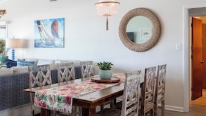 Ein Essbereich mit Holztisch, einer Tischdecke mit Blumenmuster und einem gewebten Spiegel.