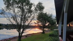 Vista de un lago con árboles y un atardecer.