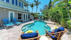 A pool area with lounge chairs and a house in the background. - Coquina Sands - Pool Home with Beach Views - Powered by Island Real Estate (Holmes Beach)