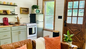 A cozy living room with a brown leather couch, a white blanket, and a wooden door with a window.