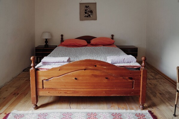 Ein Bett mit Holzkopfstück, zwei Kissen und einer Decke.