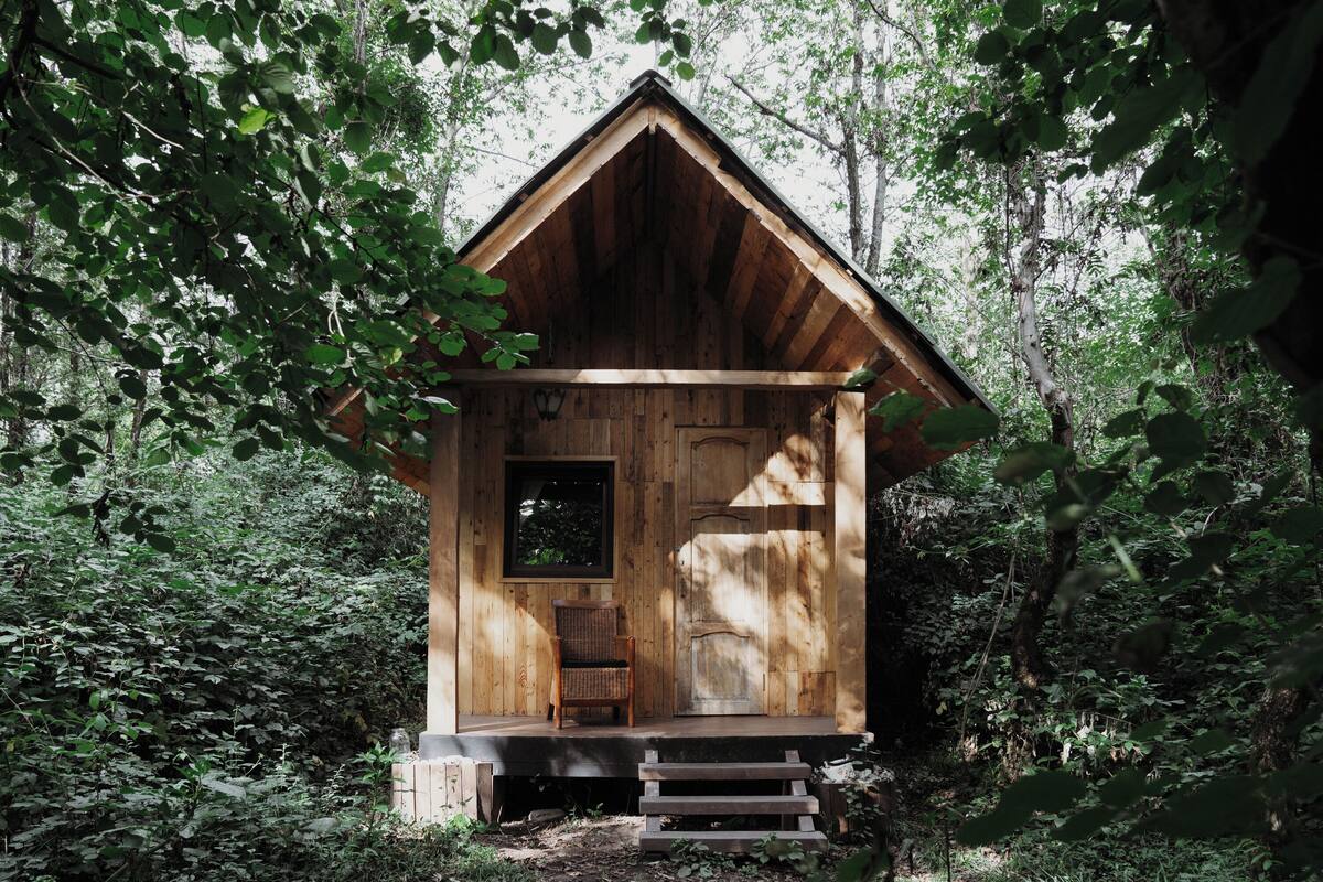 Une cabane en bois avec un toit à deux versants, une porte d’entrée et une fenêtre.
