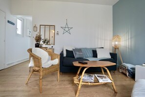 A living room with a dark blue sofa, a wicker chair, a round coffee table, and a floor lamp.