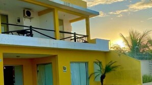 A two-story yellow building with a balcony, a wheelchair-accessible parking space, and a clear sky. - Pousada A Praia (Parnamirim)