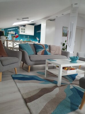 A modern living room with a grey sofa, a white coffee table, and a blue rug. - Johanna House -Dream apartament , looking for the sky,bright and cosy (București)