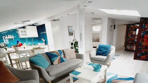 Ein modernes Wohnzimmer mit einem grauen Sofa, einem weißen Couchtisch und einem gemusterten Teppich.