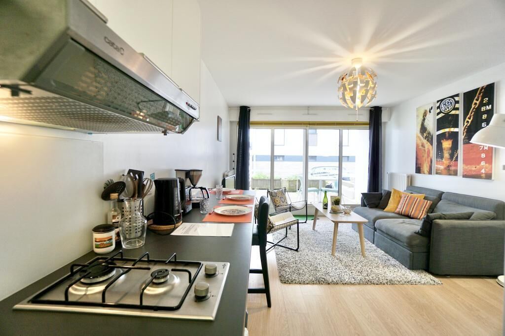 A compact living space with a kitchenette, a dining area, and a seating area with a sofa and a table.
