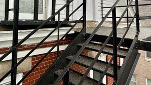 Un edificio blanco con una escalera de metal negro que conduce a una puerta.