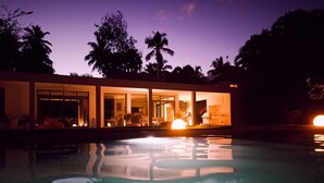 Una casa moderna con piscina al anochecer.