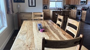 A dining area with a large wooden table and chairs, a chandelier, and wooden cabinets in a modern kitchen. - Family friendly, quiet new neighborhood (Missoula)