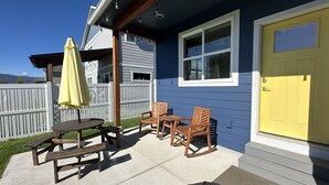 A patio with a picnic table and chairs, a yellow door, and a white fence in the background. - Family friendly, quiet new neighborhood (Missoula)