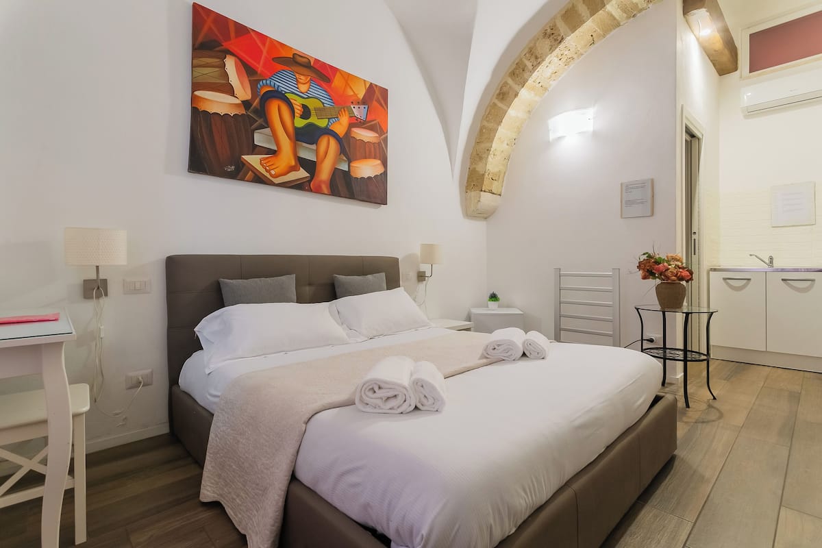 Ein modernes Hotelzimmer mit einem großen Bett, einem Schreibtisch und einem Gemälde an der Wand.