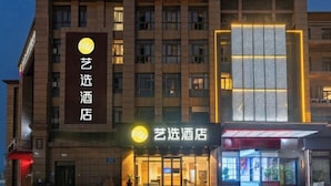 Ett hotell med en framträdande skylt som visar texten ”艺选酒店” och en modern fasad med stora fönster.