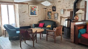 A cozy living room with a sofa, chairs, a table, and a fireplace. - Sweet Home (Bélâbre)