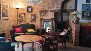A cozy living room with a fireplace, a sofa, a coffee table, and various artworks on the walls. - Sweet Home (Bélâbre)