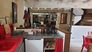 A compact kitchen with a red countertop, a small white dishwasher, and a coffee maker. - Sweet Home (Bélâbre)