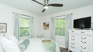 Un dormitorio con cama, ventilador de techo, cómoda y televisor.