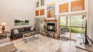 Ein geräumiges Wohnzimmer mit Kamin, einer Couch, einem Couchtisch und Blick auf eine Terrasse.