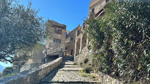 A cobblestone path leading to traditional stone buildings with balconies, surrounded by greenery. - Apartement town Center, Rénové, 90m2 with balcony (saint florent)