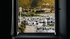 A view from a window overlooking a marina with boats, a hilly landscape, and buildings in the background. - Apartement town Center, Rénové, 90m2 with balcony (saint florent)