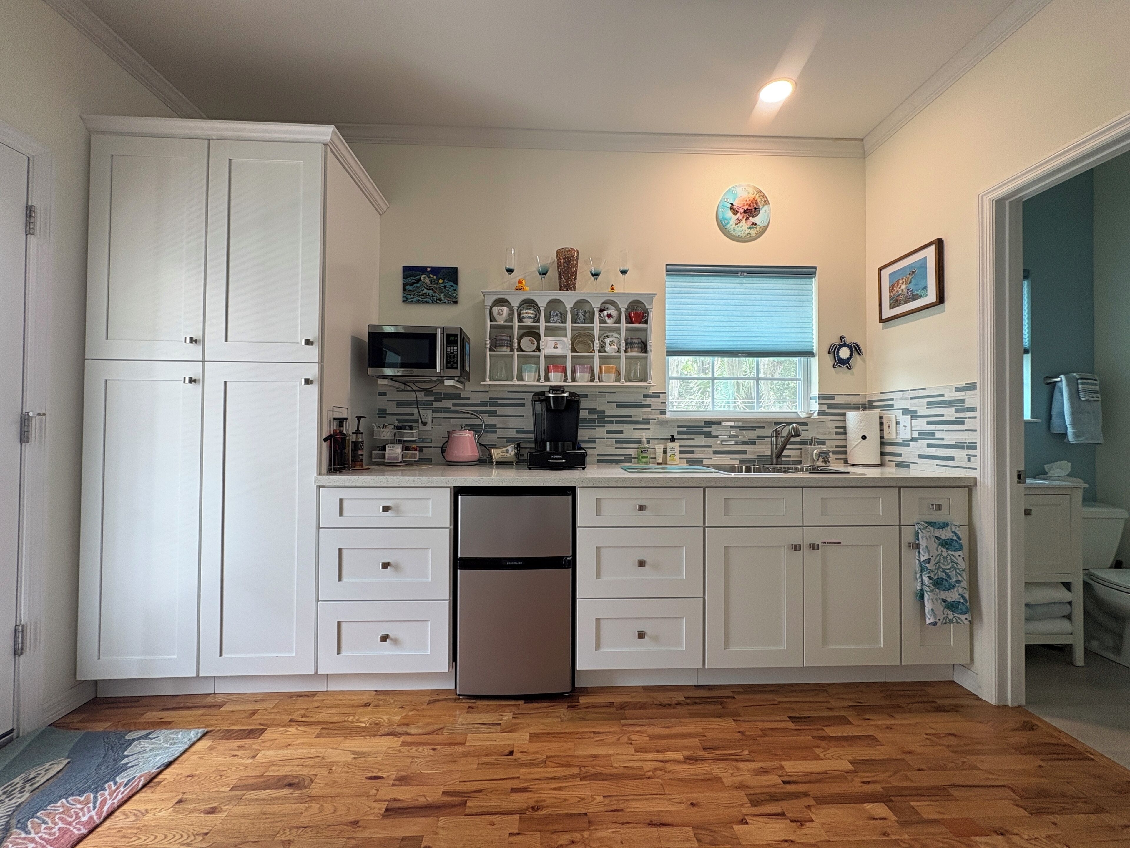 A kitchen with white cabinets, a microwave, a coffee maker, and a dishwasher.